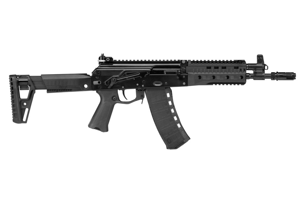A side view of a modern tactical rifle with a black finish, featuring a collapsible stock, a quad rail for attachments, and a curved magazine.