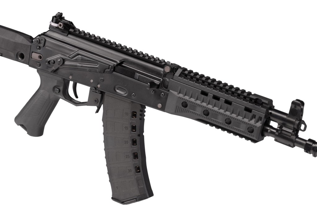 A close-up view of a modern black assault rifle with a curved magazine and tactical accessories.